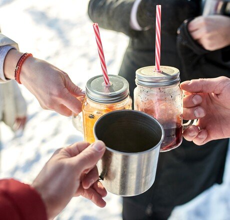 Close up image of group friends cheering with mulled wine in winter forest