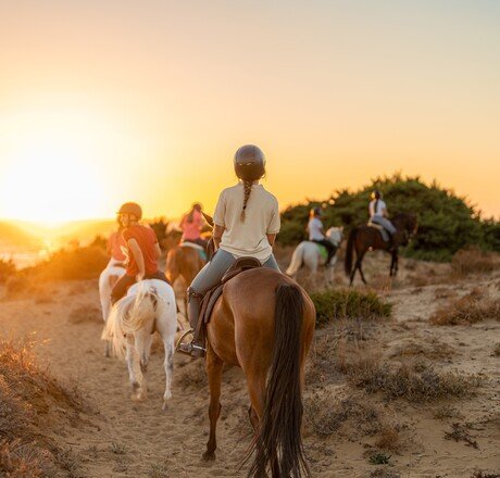 group of young riders on horseback heading towards the beach. Sea