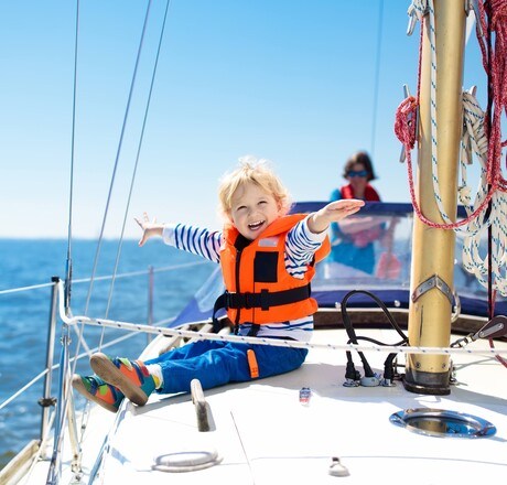 Kids sail on yacht in sea. Child sailing on boat. Little boy in safe life jackets travel on ocean ship. Children enjoy yachting cruise. Summer vacation for family. Young sailor on sailboat front deck.